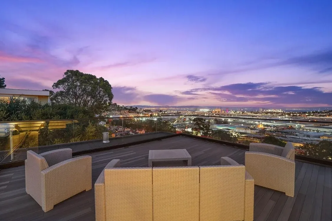 Modern roof deck with glass railings overlooking San Francisco at dusk
